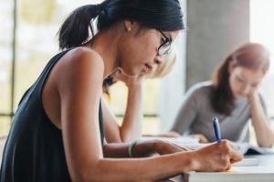 Close,Up,Shot,Of,Young,Woman,Writing,Notes,With,Classmates
