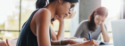 Close,Up,Shot,Of,Young,Woman,Writing,Notes,With,Classmates